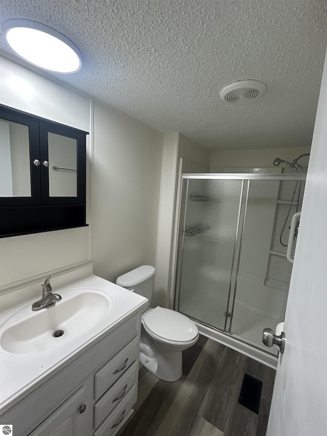 bathroom with hardwood / wood-style floors, vanity, toilet, and an enclosed shower