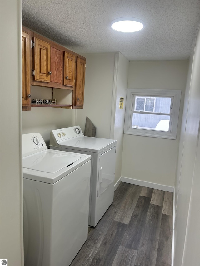 laundry area with dark wood-type flooring, cabinets, a textured ceiling, and independent washer and dryer