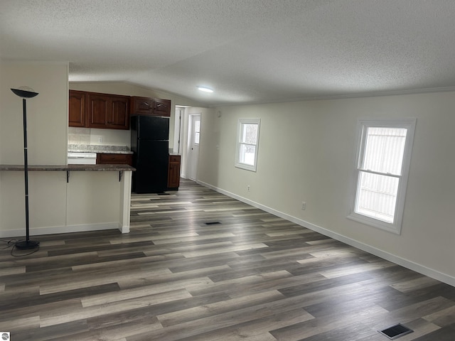 kitchen with dark hardwood / wood-style flooring, lofted ceiling, black refrigerator, and plenty of natural light