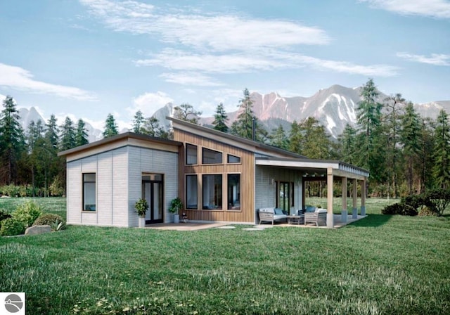 rear view of property featuring a mountain view, a patio area, and a yard