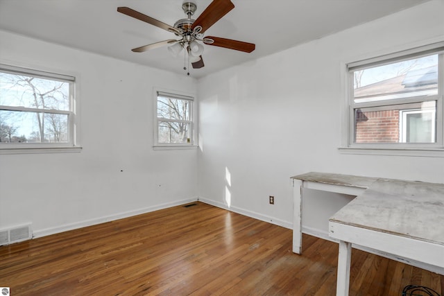 empty room with dark hardwood / wood-style floors, ceiling fan, and a healthy amount of sunlight