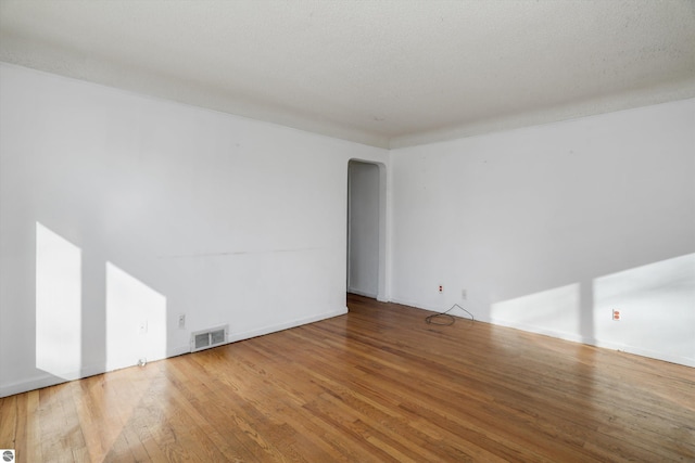 empty room featuring a textured ceiling and hardwood / wood-style flooring