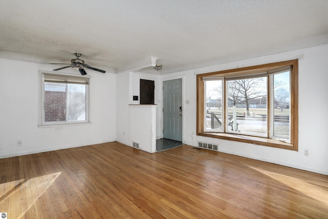 unfurnished living room with wood-type flooring, a textured ceiling, and ceiling fan