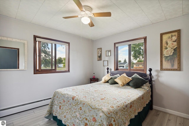 bedroom featuring baseboard heating, ceiling fan, and light hardwood / wood-style flooring