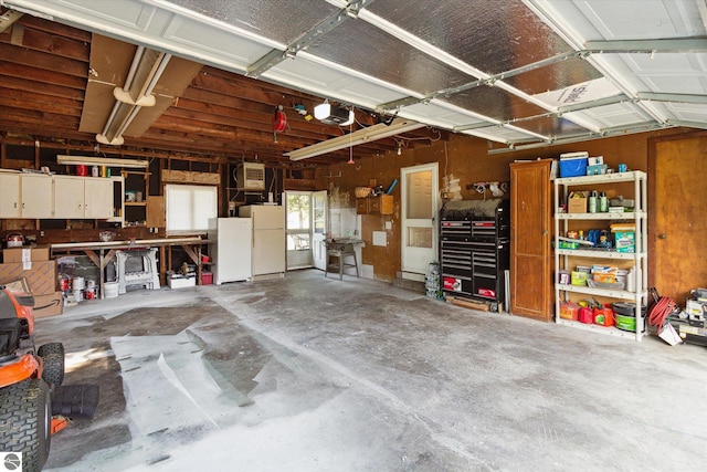 garage with a workshop area, a garage door opener, and white refrigerator