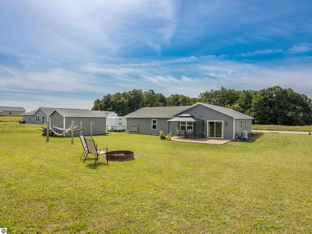 back of house with a yard, a patio, and a fire pit