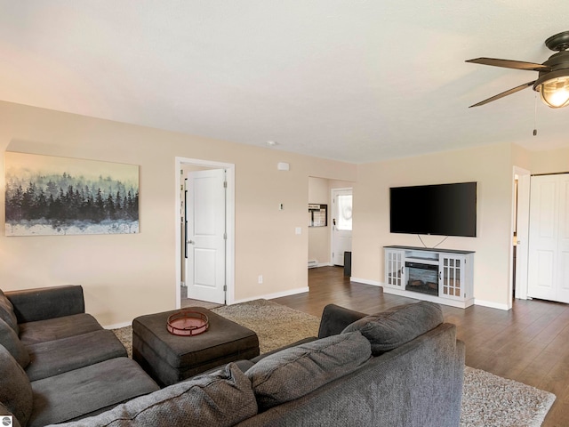 living room with ceiling fan and dark wood-type flooring