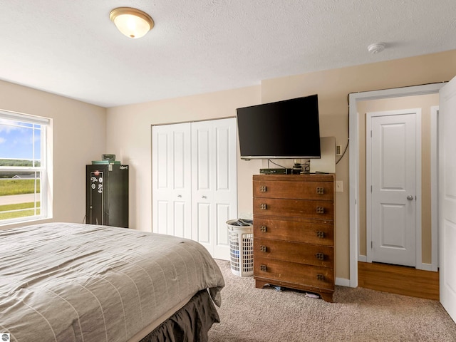 carpeted bedroom with a textured ceiling and a closet