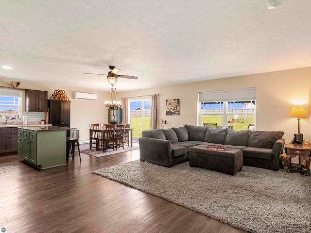 living room featuring a textured ceiling, ceiling fan with notable chandelier, dark hardwood / wood-style floors, and a wall unit AC