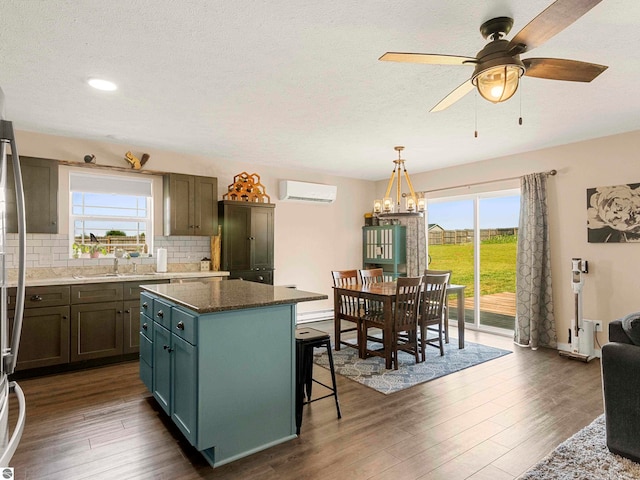 kitchen featuring a wall mounted air conditioner, a center island, sink, hanging light fixtures, and decorative backsplash