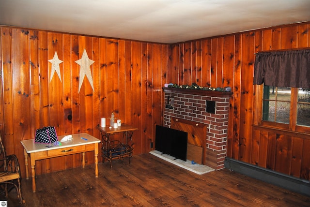 living room with wood walls, a baseboard heating unit, dark hardwood / wood-style flooring, and a brick fireplace