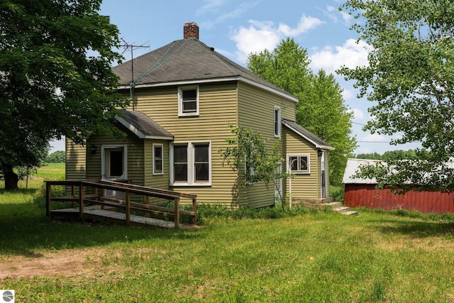 rear view of house featuring a wooden deck and a yard