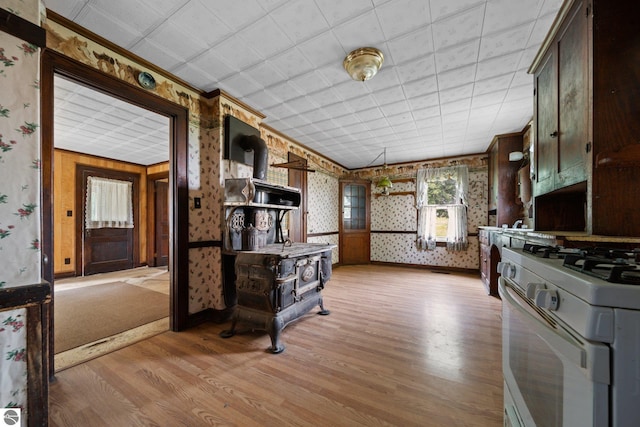 kitchen with ornamental molding, dark brown cabinetry, light hardwood / wood-style floors, and white gas stove