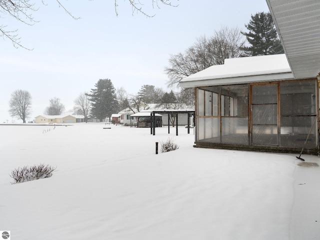 snowy yard featuring a sunroom