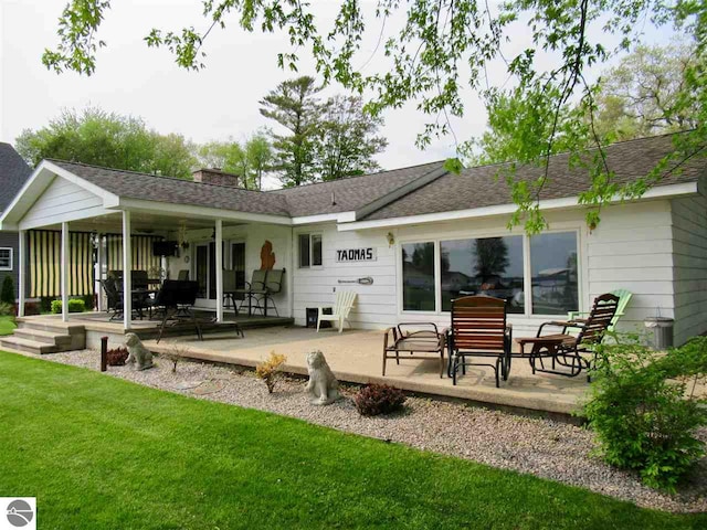 back of property featuring a lawn and a patio