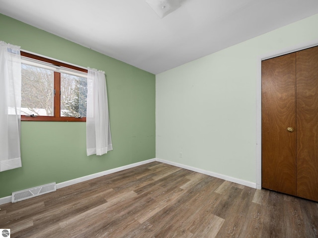 unfurnished bedroom with dark wood-type flooring and a closet