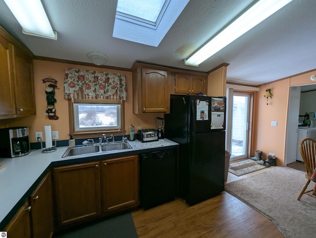 kitchen featuring black appliances, sink, a textured ceiling, light hardwood / wood-style floors, and washer / clothes dryer