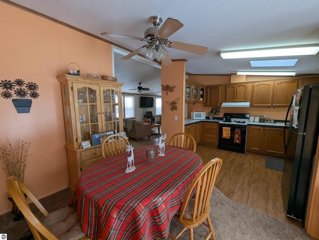 dining room featuring ceiling fan, crown molding, dark wood-type flooring, and vaulted ceiling