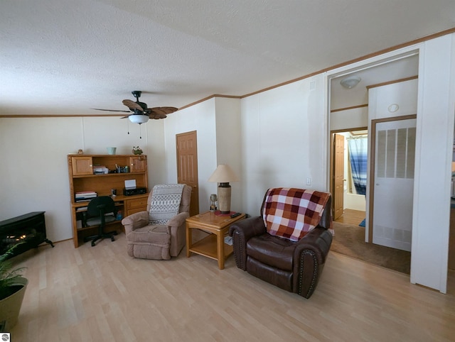 sitting room featuring a textured ceiling, light wood-type flooring, ceiling fan, and ornamental molding