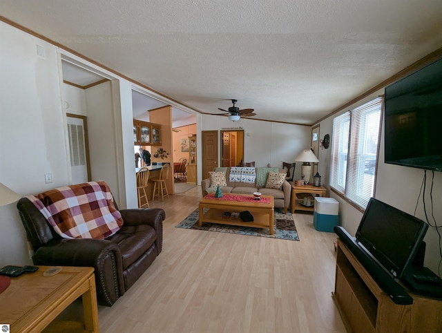 living room featuring crown molding, light hardwood / wood-style flooring, ceiling fan, and a textured ceiling