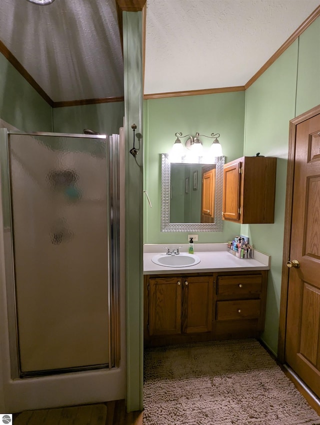 bathroom featuring vanity, a shower with shower door, and crown molding