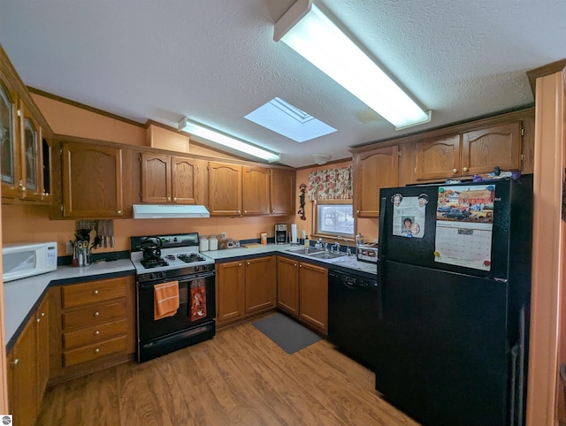 kitchen with sink, lofted ceiling with skylight, light hardwood / wood-style floors, a textured ceiling, and black appliances