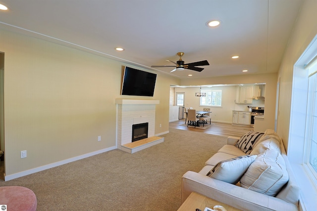 carpeted living room with ceiling fan and a brick fireplace