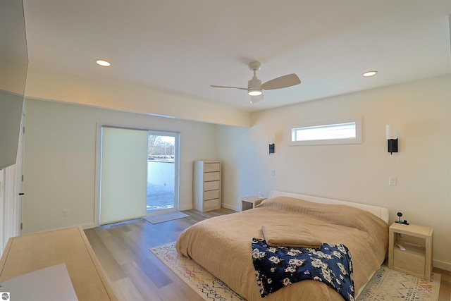 bedroom featuring ceiling fan, light hardwood / wood-style floors, access to exterior, and multiple windows