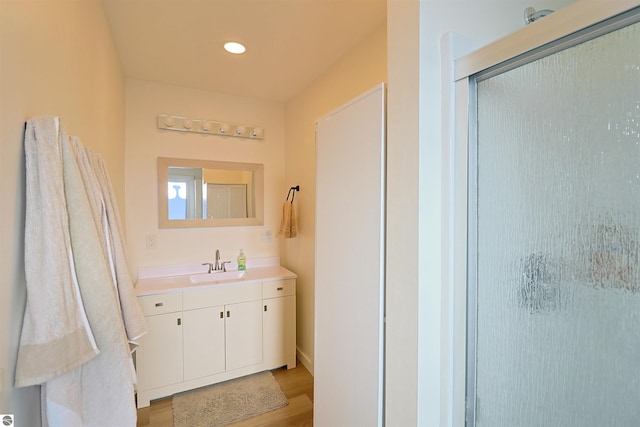 bathroom with hardwood / wood-style flooring, vanity, and a shower with door