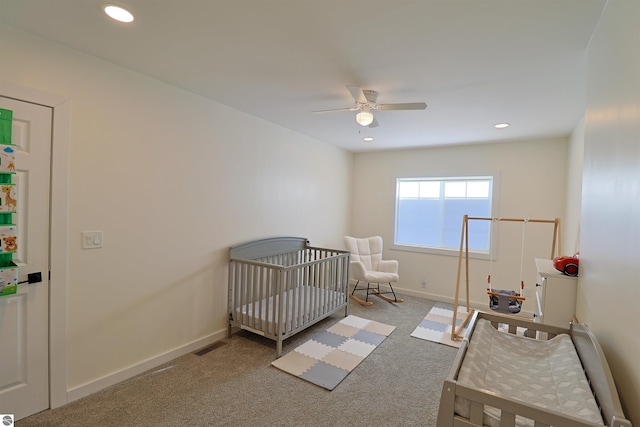 bedroom featuring ceiling fan, a nursery area, and light carpet