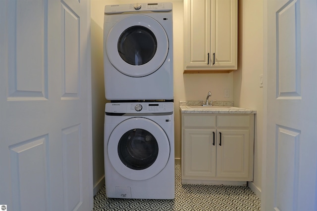 washroom with cabinets, light tile patterned floors, stacked washer and clothes dryer, and sink