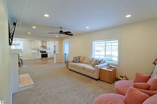 living room featuring ceiling fan, light colored carpet, and a brick fireplace