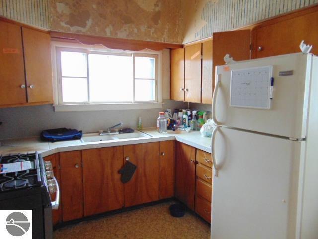 kitchen featuring black range with gas stovetop, sink, and white fridge