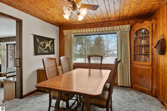 dining room featuring wood ceiling, light colored carpet, ceiling fan, and wooden walls