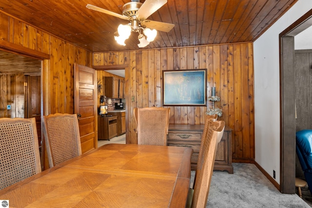 dining area with light carpet, ceiling fan, wood walls, and wooden ceiling