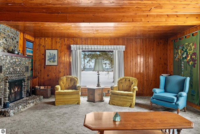 carpeted living area with a fireplace, wood ceiling, and wooden walls