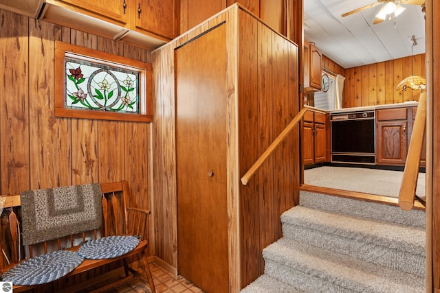 staircase featuring ceiling fan and wooden walls