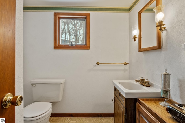 bathroom featuring toilet, baseboards, and vanity