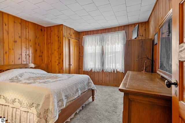 bedroom featuring wood walls and carpet