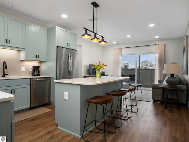 kitchen with backsplash, stainless steel appliances, dark wood-type flooring, sink, and decorative light fixtures