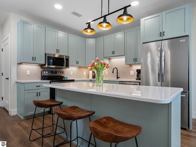 kitchen featuring a center island, stainless steel appliances, dark hardwood / wood-style floors, pendant lighting, and decorative backsplash