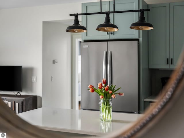 kitchen with green cabinets, stainless steel fridge, and decorative light fixtures