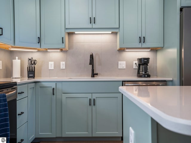 kitchen with range, backsplash, stainless steel refrigerator, and sink