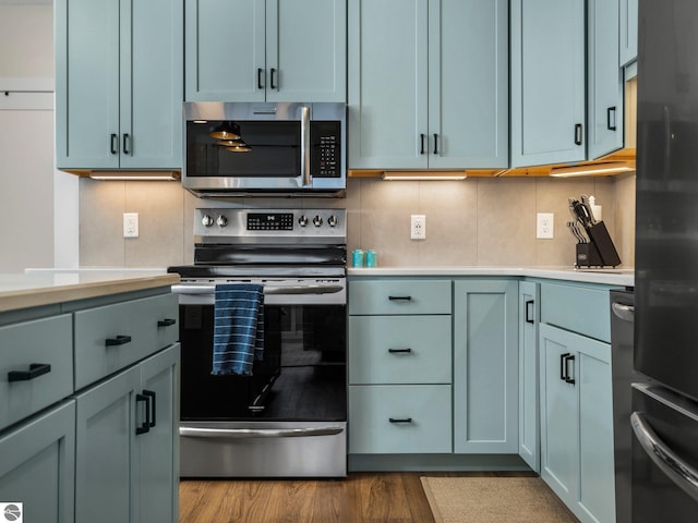 kitchen featuring backsplash, hardwood / wood-style flooring, and appliances with stainless steel finishes