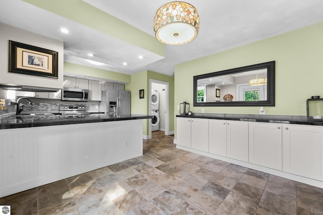 kitchen with decorative backsplash, appliances with stainless steel finishes, sink, white cabinetry, and stacked washer / drying machine