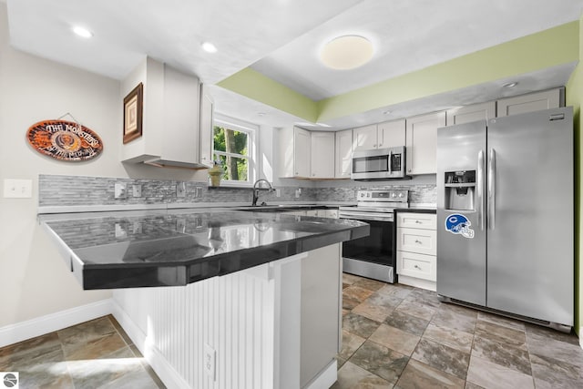 kitchen with a kitchen breakfast bar, kitchen peninsula, decorative backsplash, white cabinets, and appliances with stainless steel finishes