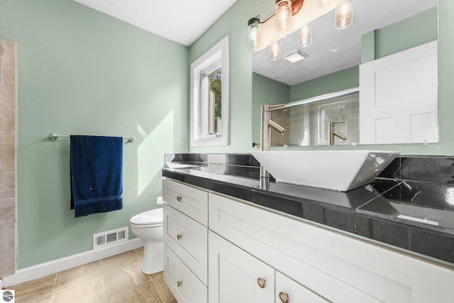 bathroom with tile patterned floors, toilet, vanity, and walk in shower