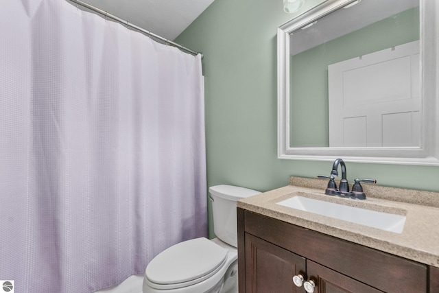 bathroom featuring curtained shower, vanity, and toilet