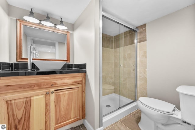 bathroom with tile patterned flooring, vanity, toilet, and a shower with shower door