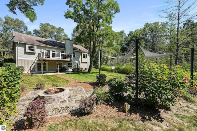 back of house featuring a fire pit, a wooden deck, a patio area, and a lawn